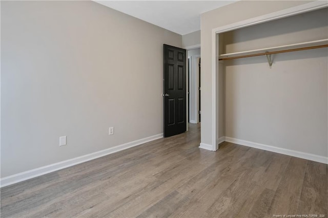 unfurnished bedroom featuring a closet, baseboards, and wood finished floors