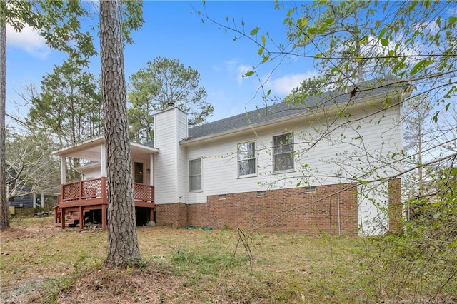 rear view of property with a deck, stairway, and a chimney