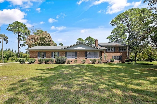 split level home featuring a front lawn, brick siding, and a chimney