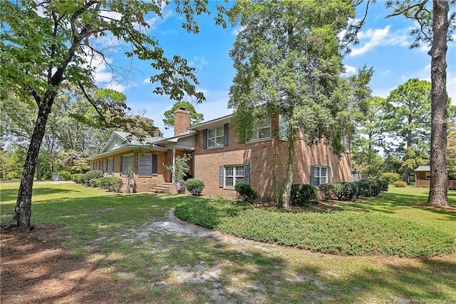 view of side of home featuring a yard, brick siding, and a chimney