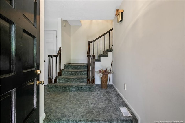 carpeted foyer entrance featuring visible vents, stairs, and baseboards