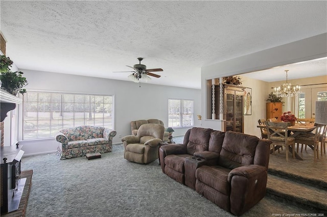 living area featuring a wealth of natural light, carpet floors, a textured ceiling, and ceiling fan with notable chandelier