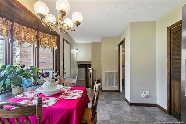 dining room with an inviting chandelier, baseboards, visible vents, and a textured ceiling