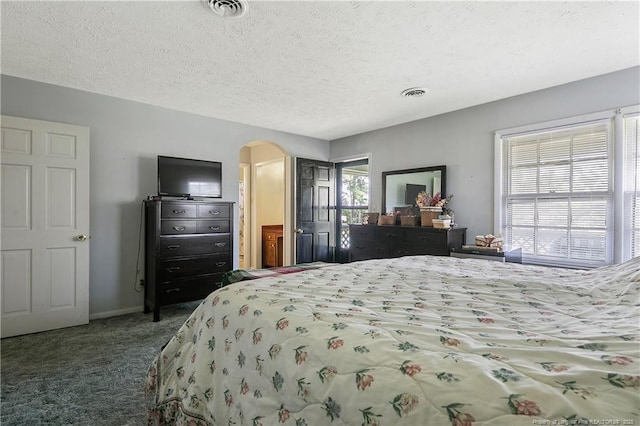 carpeted bedroom featuring arched walkways, visible vents, a textured ceiling, and baseboards