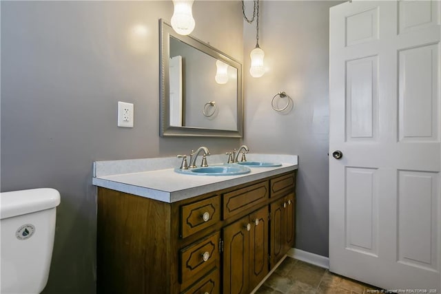 bathroom featuring toilet, vanity, and baseboards