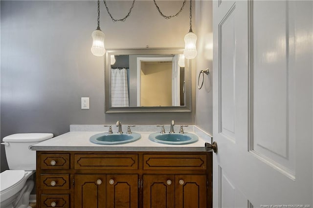 bathroom with a sink, toilet, and double vanity