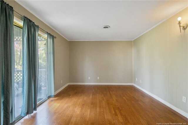 spare room with wood finished floors, visible vents, and ornamental molding