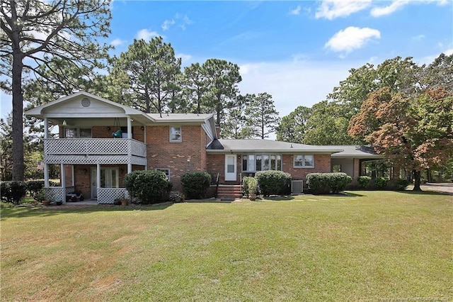 view of front of house featuring a front yard, a balcony, and brick siding