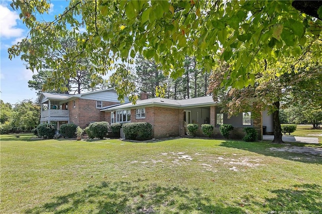 tri-level home with brick siding, a chimney, and a front lawn