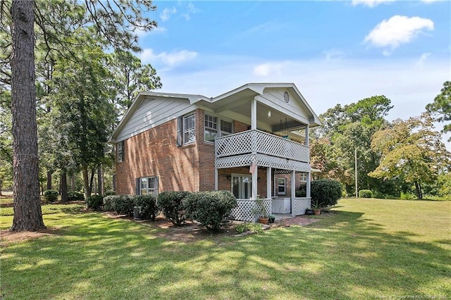 rear view of house featuring brick siding, a lawn, and a balcony