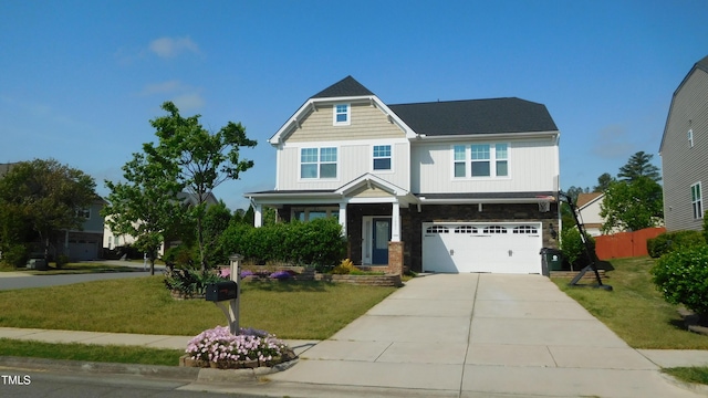 craftsman-style home featuring driveway, stone siding, fence, an attached garage, and a front yard