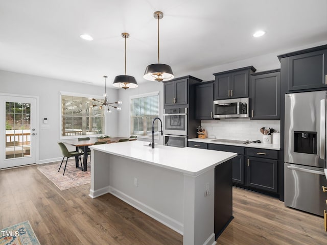 kitchen featuring tasteful backsplash, dark wood-type flooring, light countertops, appliances with stainless steel finishes, and a sink