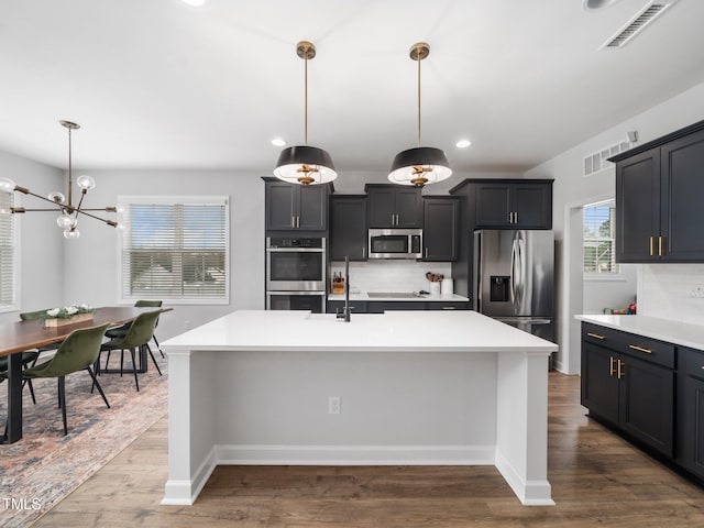 kitchen featuring visible vents, stainless steel appliances, light countertops, dark wood-type flooring, and tasteful backsplash