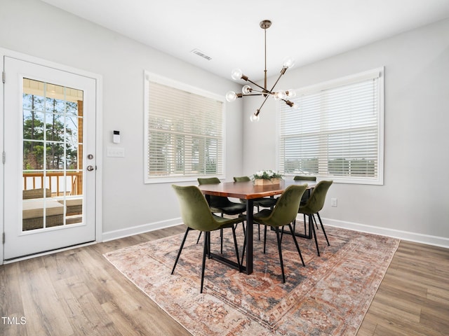 dining area featuring an inviting chandelier, wood finished floors, baseboards, and visible vents