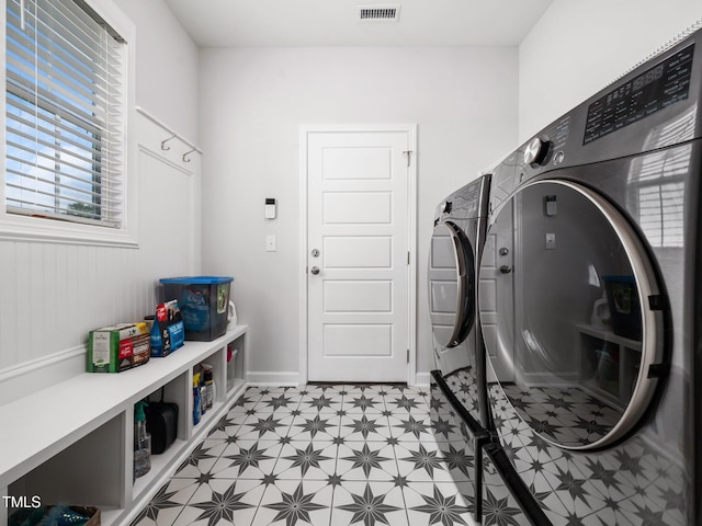 laundry room featuring light floors, baseboards, visible vents, washing machine and clothes dryer, and laundry area