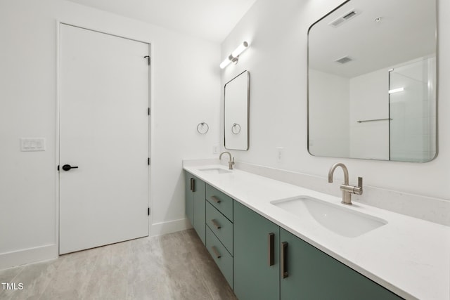 full bath with a sink, visible vents, wood finished floors, and double vanity