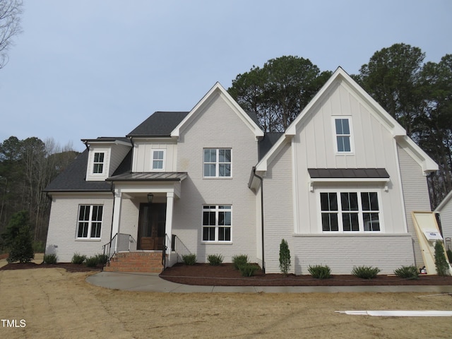 modern farmhouse style home featuring metal roof, brick siding, board and batten siding, and a standing seam roof