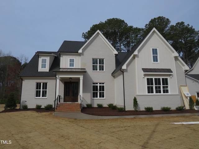 view of front of house featuring metal roof, brick siding, board and batten siding, and a standing seam roof