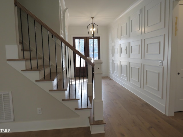 entryway featuring visible vents, baseboards, a chandelier, stairway, and wood finished floors