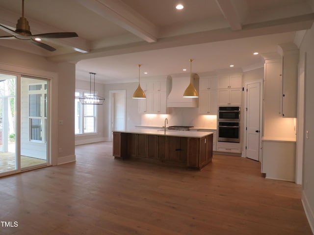 kitchen featuring a ceiling fan, wood finished floors, custom exhaust hood, beam ceiling, and white cabinets