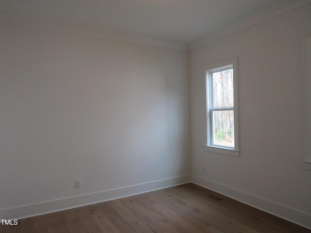 spare room with visible vents, crown molding, baseboards, and wood finished floors