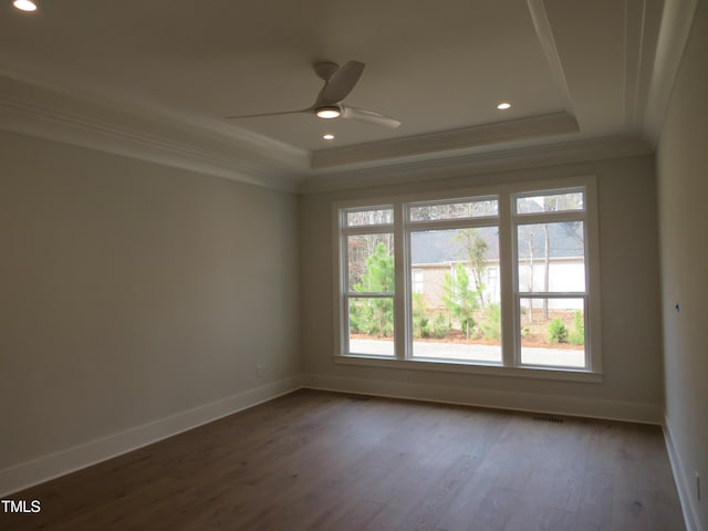 spare room featuring wood finished floors, baseboards, a tray ceiling, ceiling fan, and crown molding