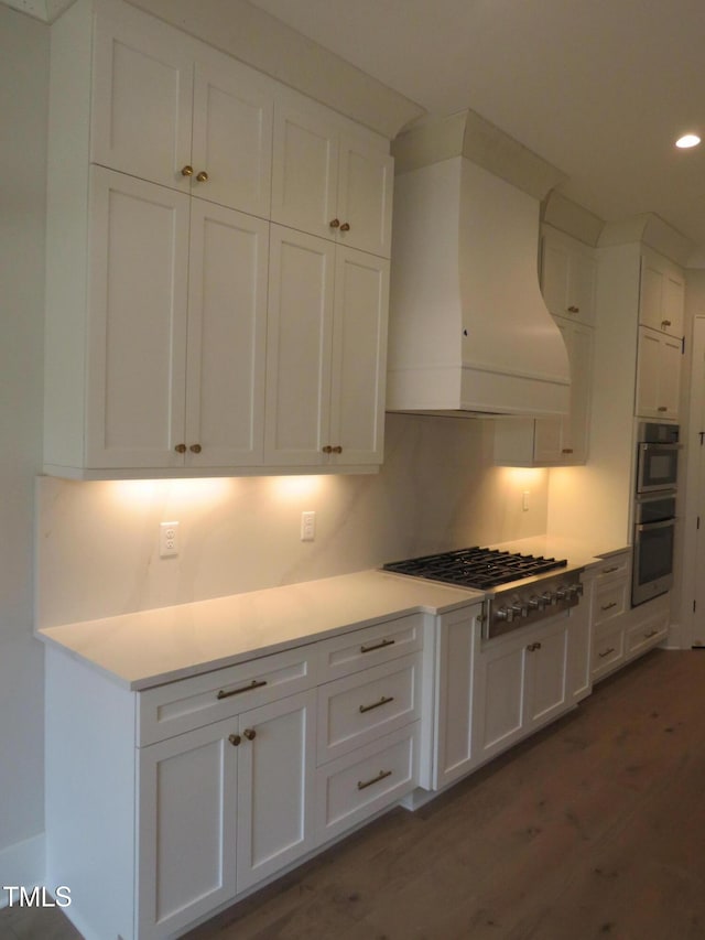 kitchen featuring custom range hood, gas stovetop, double oven, white cabinets, and dark wood-style flooring