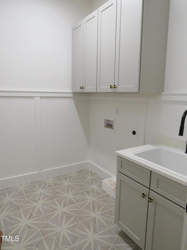 laundry area with hookup for a washing machine, baseboards, hookup for an electric dryer, cabinet space, and a sink