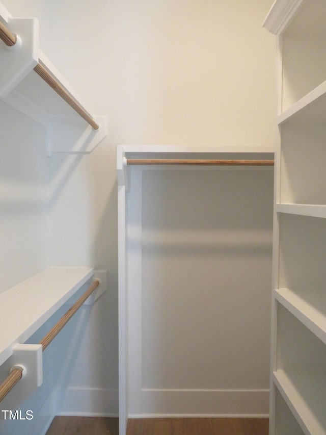 walk in closet with wood finished floors