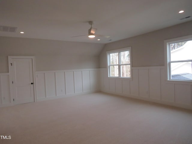 empty room featuring visible vents, a wainscoted wall, light colored carpet, and ceiling fan