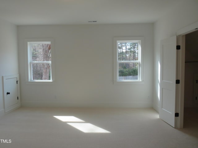 unfurnished bedroom with visible vents, multiple windows, baseboards, and carpet