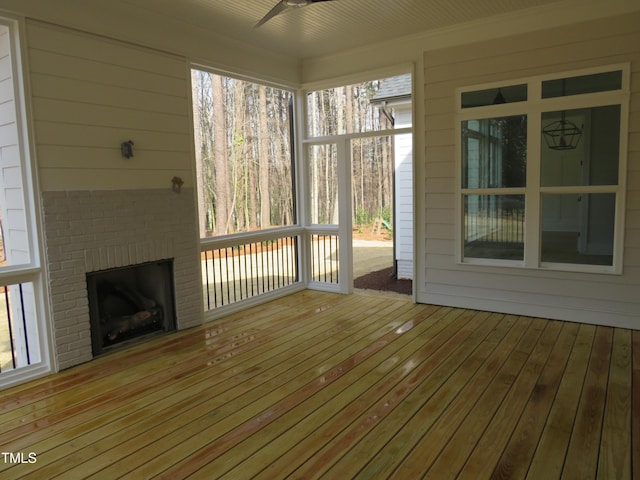 unfurnished sunroom featuring an outdoor brick fireplace and ceiling fan