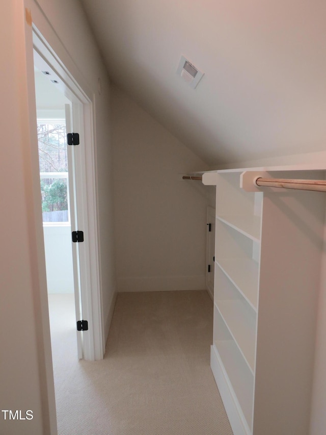 walk in closet with lofted ceiling, visible vents, and light carpet