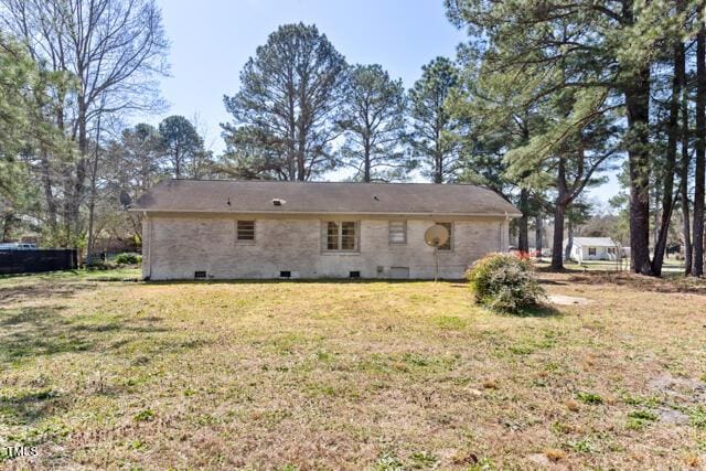 rear view of property featuring crawl space and a lawn