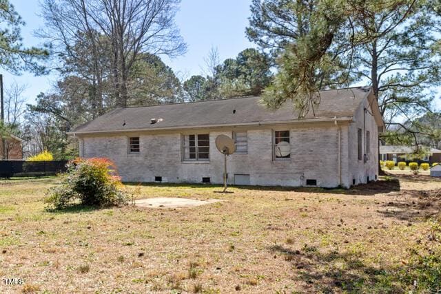 back of house featuring crawl space and a lawn