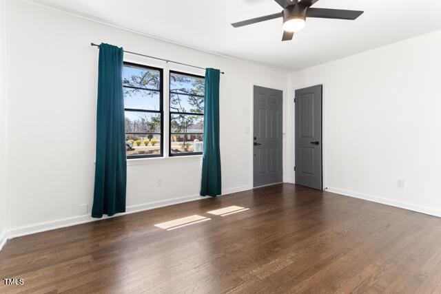 empty room featuring baseboards, wood finished floors, and a ceiling fan