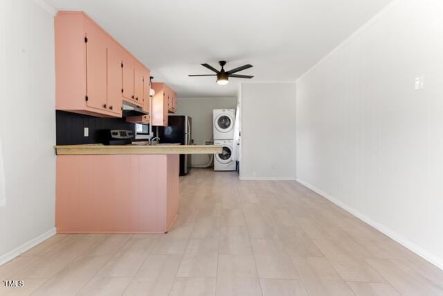 kitchen featuring ceiling fan, under cabinet range hood, light countertops, stacked washer and clothes dryer, and a peninsula