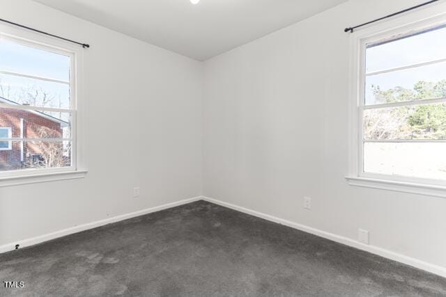 unfurnished room featuring dark colored carpet, baseboards, and plenty of natural light