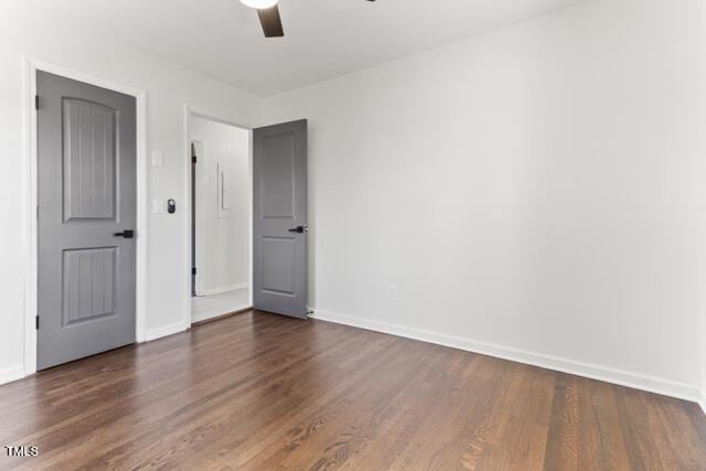 unfurnished room featuring baseboards, ceiling fan, and dark wood finished floors