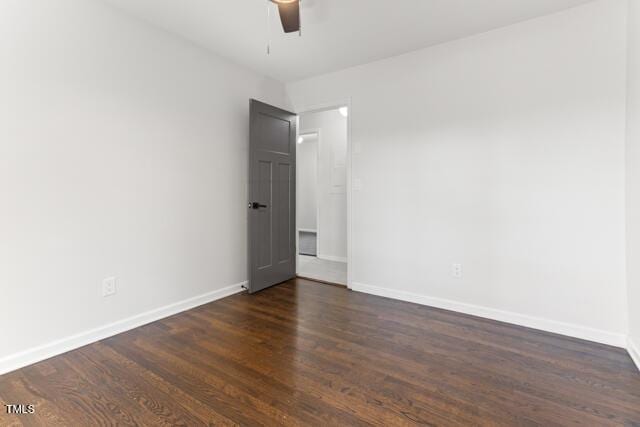 spare room with ceiling fan, dark wood-type flooring, and baseboards