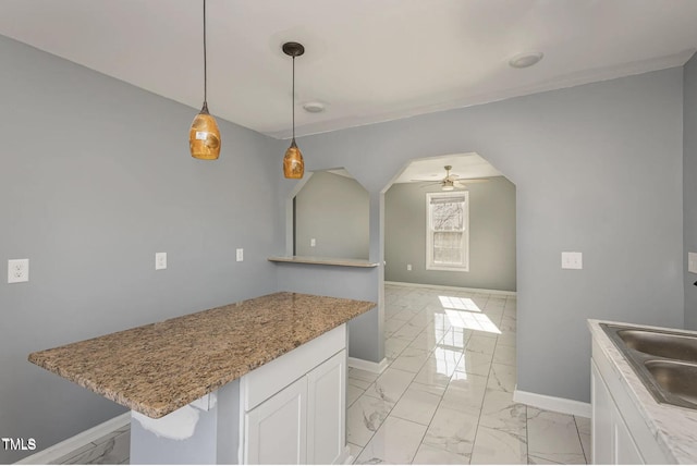 kitchen featuring white cabinets, baseboards, marble finish floor, and ceiling fan