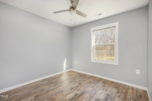 unfurnished room with visible vents, a ceiling fan, baseboards, and wood finished floors