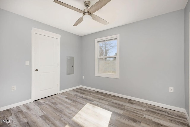 spare room featuring electric panel, baseboards, ceiling fan, and wood finished floors