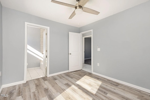 unfurnished bedroom with ceiling fan, connected bathroom, baseboards, and wood finished floors