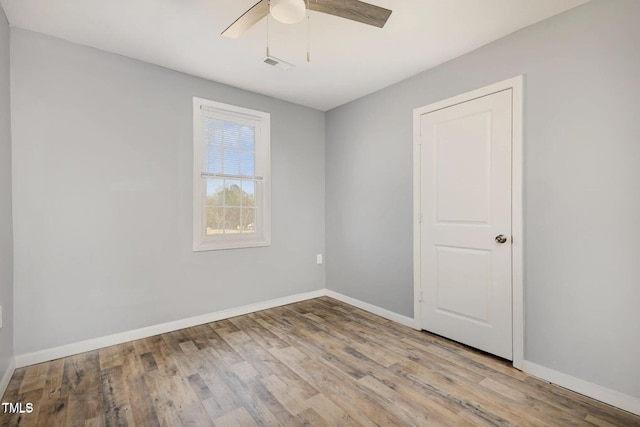 empty room featuring visible vents, baseboards, wood finished floors, and a ceiling fan