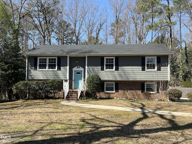 raised ranch with brick siding, a front yard, and fence