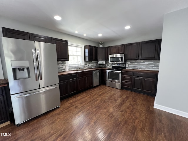 kitchen with decorative backsplash, stainless steel appliances, dark wood-type flooring, and a sink