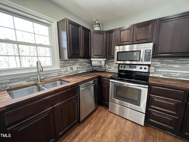 kitchen featuring a sink, dark brown cabinets, butcher block counters, stainless steel appliances, and dark wood-style flooring