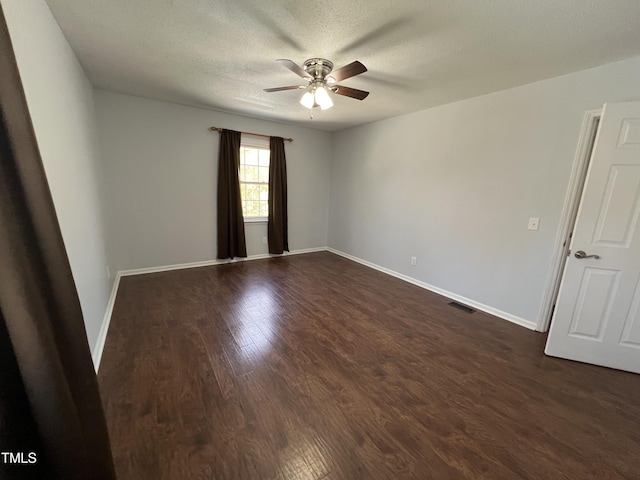 empty room with visible vents, dark wood-type flooring, baseboards, ceiling fan, and a textured ceiling