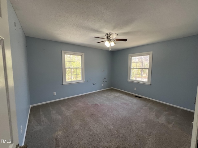 carpeted spare room with a ceiling fan, a healthy amount of sunlight, visible vents, and a textured ceiling